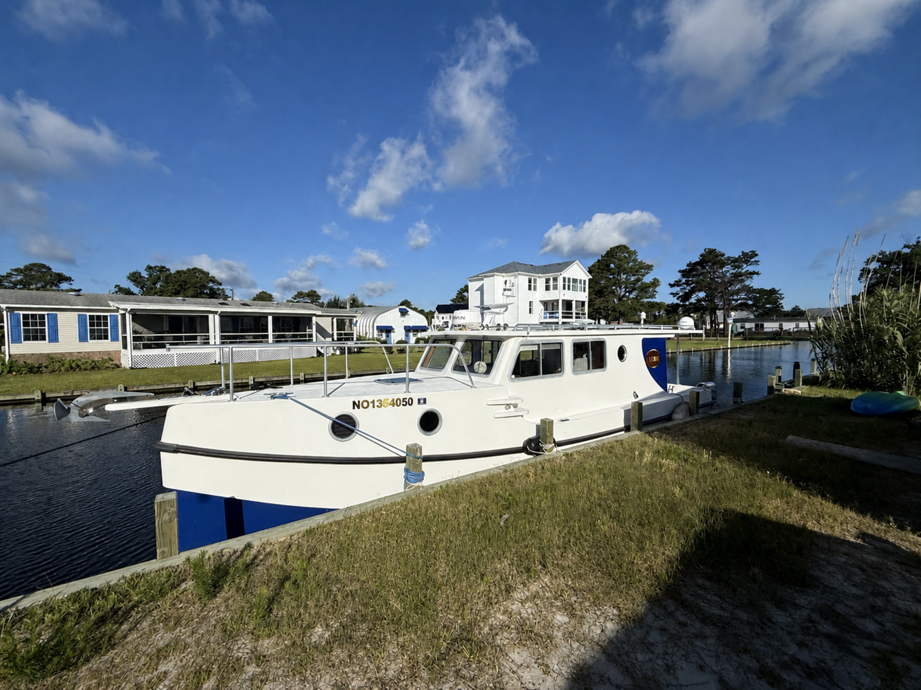 Ulysses tied alongside her home dock on a clear morning, showing the enclosed pilothouse, forward cabin, and bow rail.
